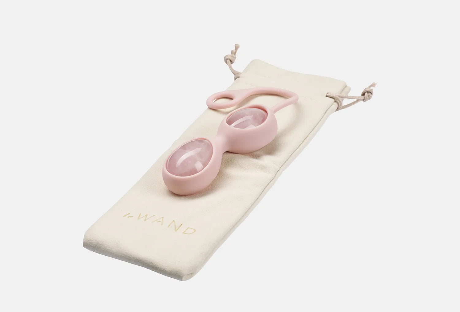 Ovos yoni de quartzo rosa de cor rosa da marca Le Wand pousados em cima de uma bolsa de algodão