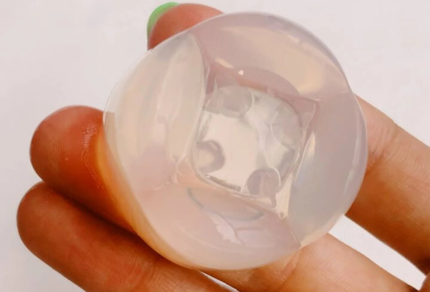 Estimulador clitoriano sem motor Iroha Petit Lily em silicone transparente — segurado na mão