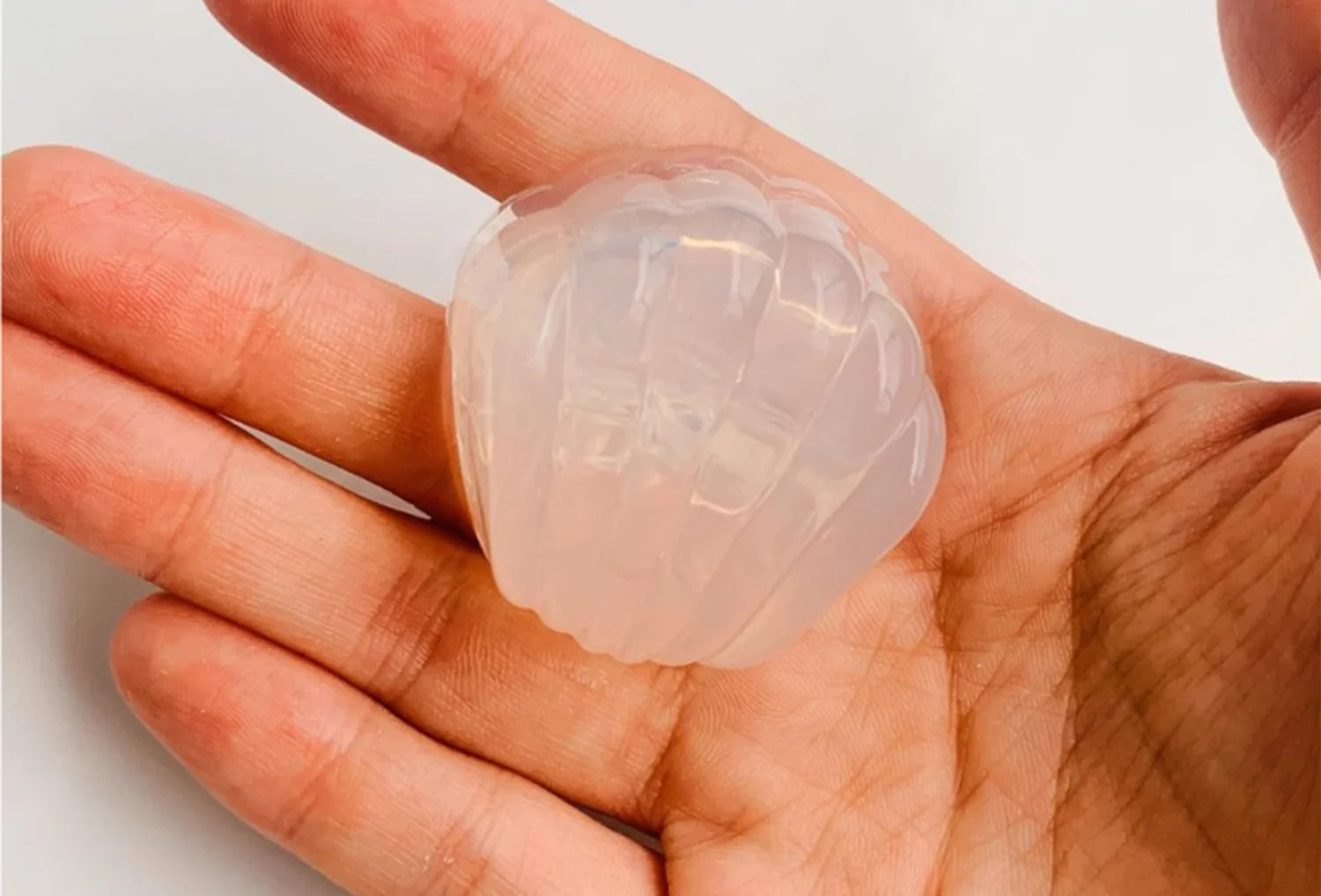 Estimulador clitoriano sem motor Iroha Petit Shell em silicone transparente — segurado na mão