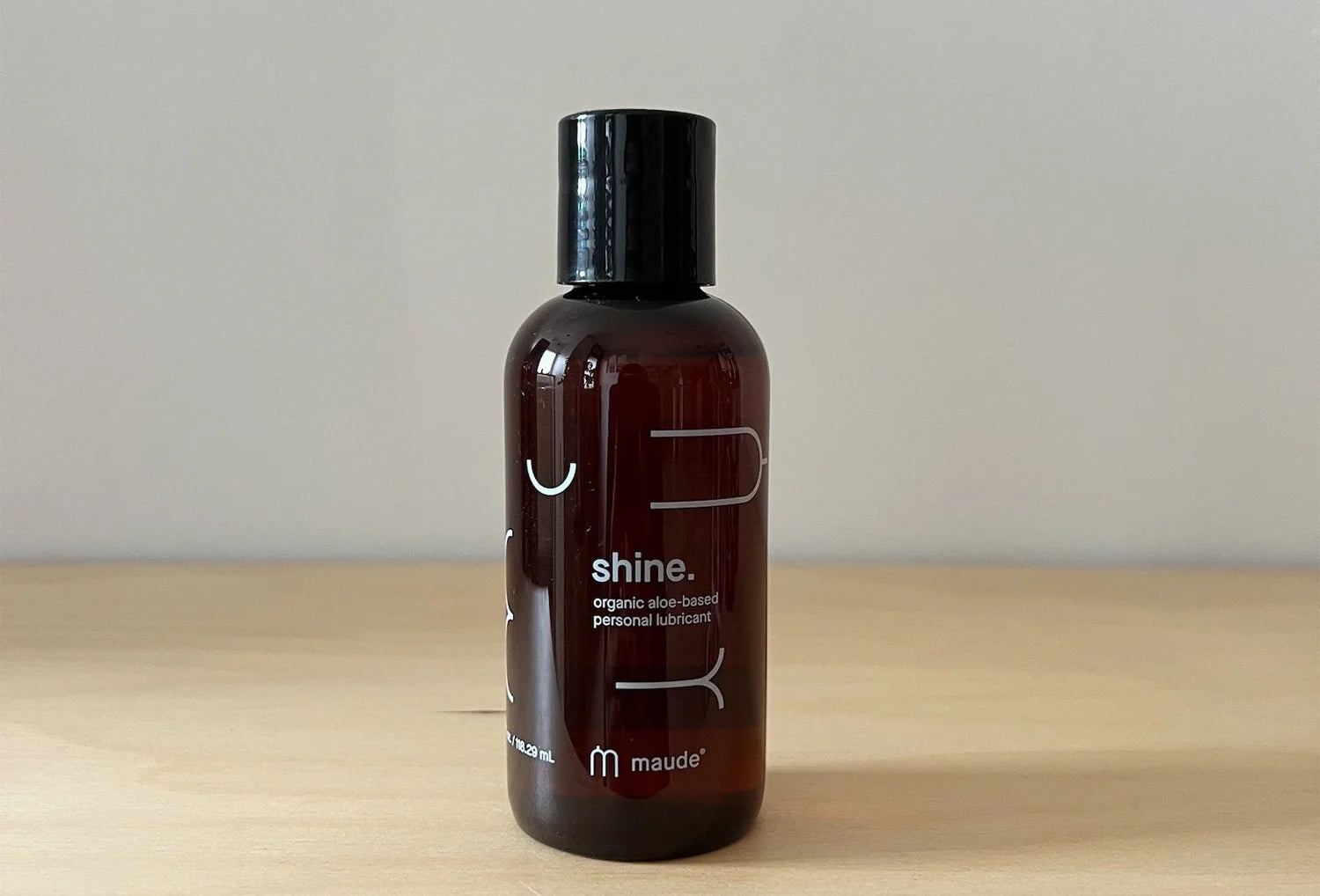 Lubrificante íntimo orgânico Maude Shine à base de água, frasco de 118 ml em cima de uma mesa de madeira castanho claro