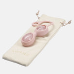 Ovos yoni de quartzo rosa de cor rosa da marca Le Wand pousados em cima de uma bolsa de algodão