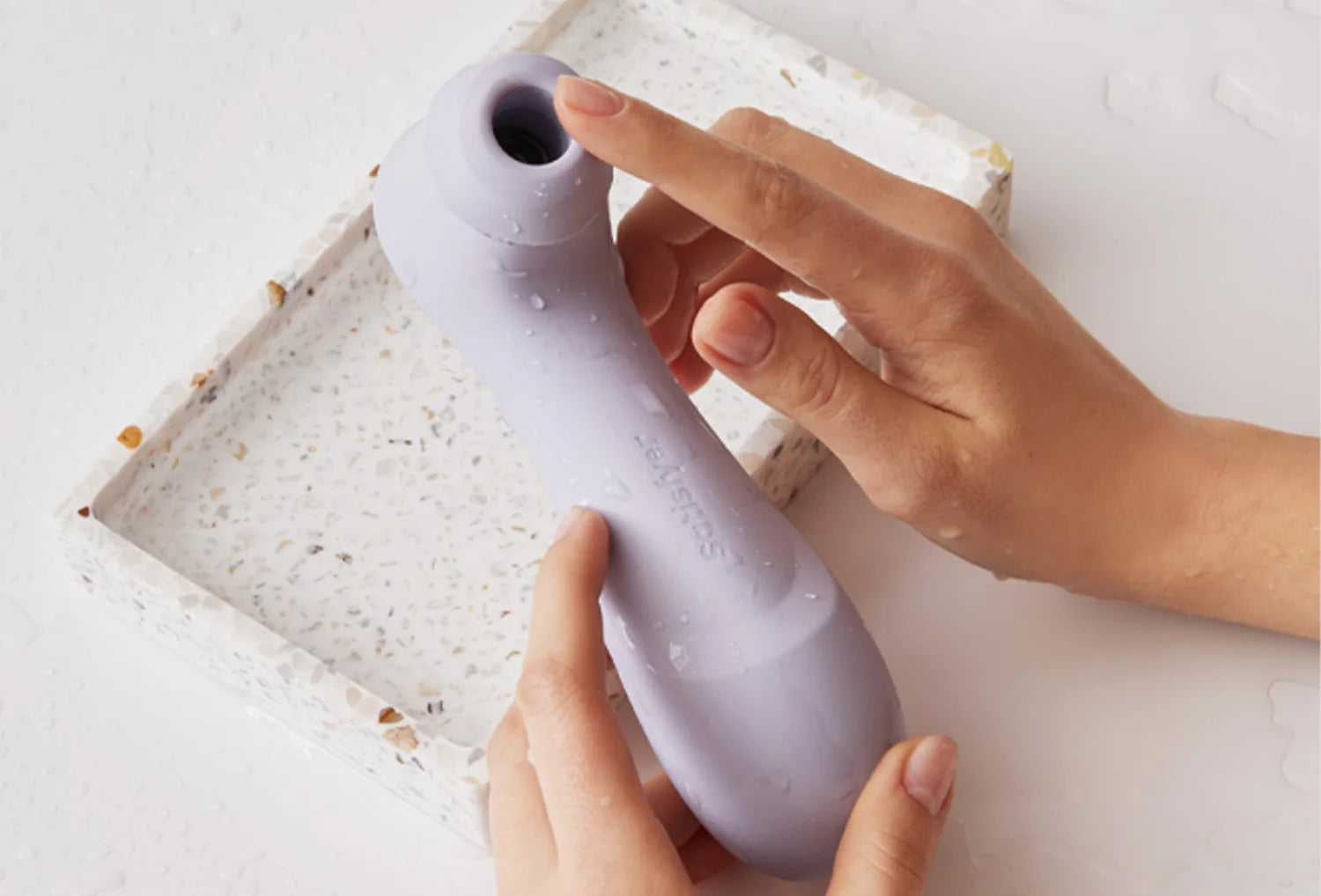 Sugador de clitóris Satisfyer Pro 2 em silicone de cor lavanda — segurado na mão com destaque da abertura