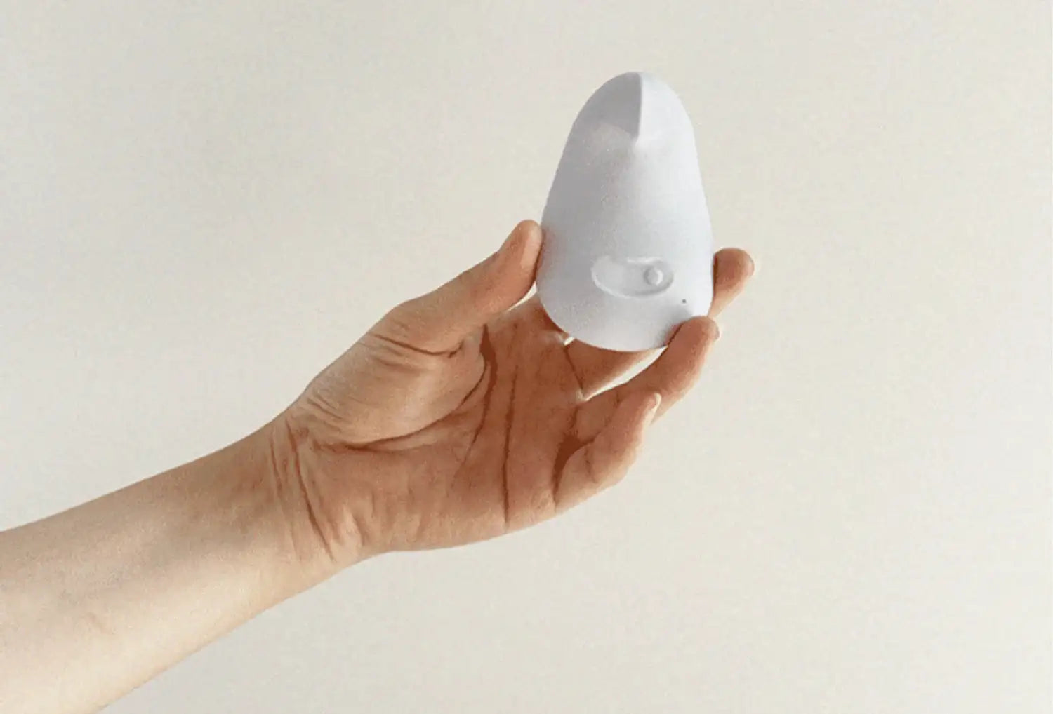 Vibrador clitoriano Dame Pom em silicone de cor lavanda — segurado na mão
