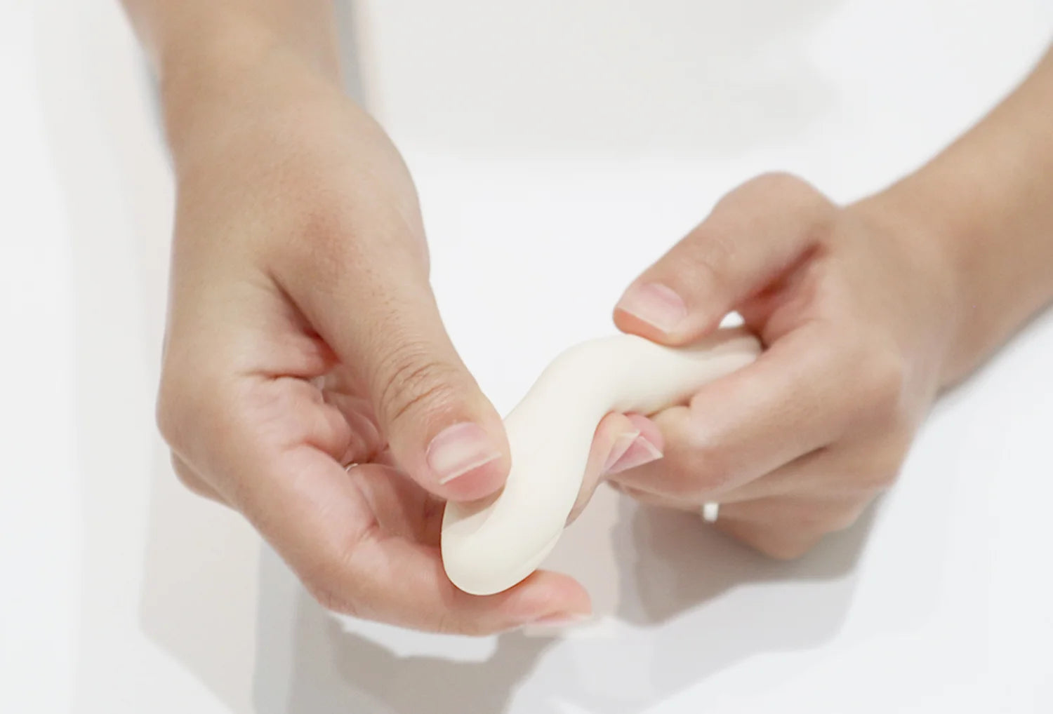 Vibrador clitoriano Iroha Koharu em silicone de cor marfim — zoom de mãos de uma pessoa vista de branco